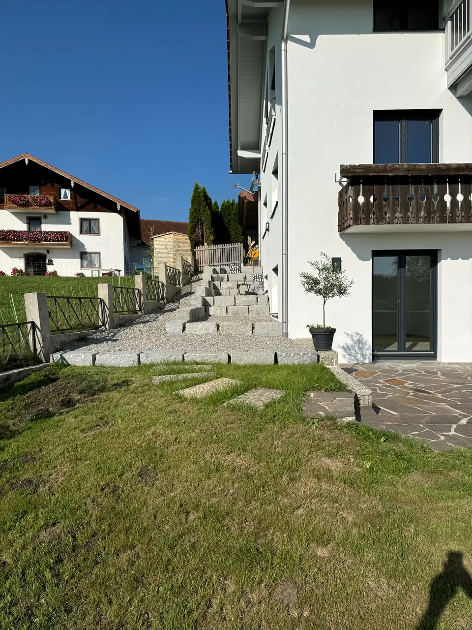 Treppe aus Granitblockstufen am Hang neben einem weißen Wohnhaus